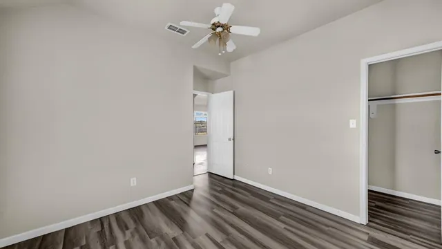 a view of a room with wooden floor and a ceiling fan