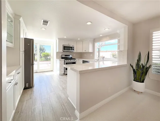 a kitchen with stainless steel appliances a refrigerator sink and wooden floor