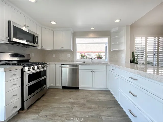 a kitchen with white cabinets stainless steel appliances and window