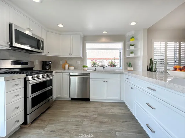 a kitchen with white cabinets stainless steel appliances and window