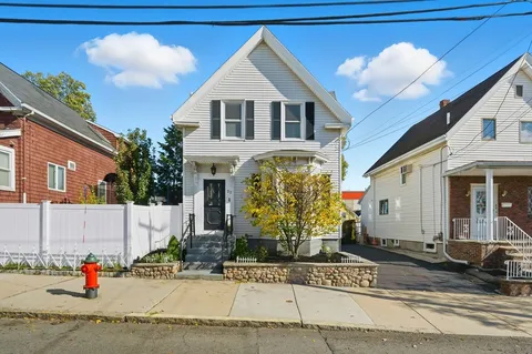 a view of a white house with large windows next to a road