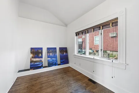 a view of an empty room with window and wooden floor