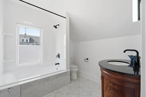 a bathroom with a granite countertop sink a toilet and shower