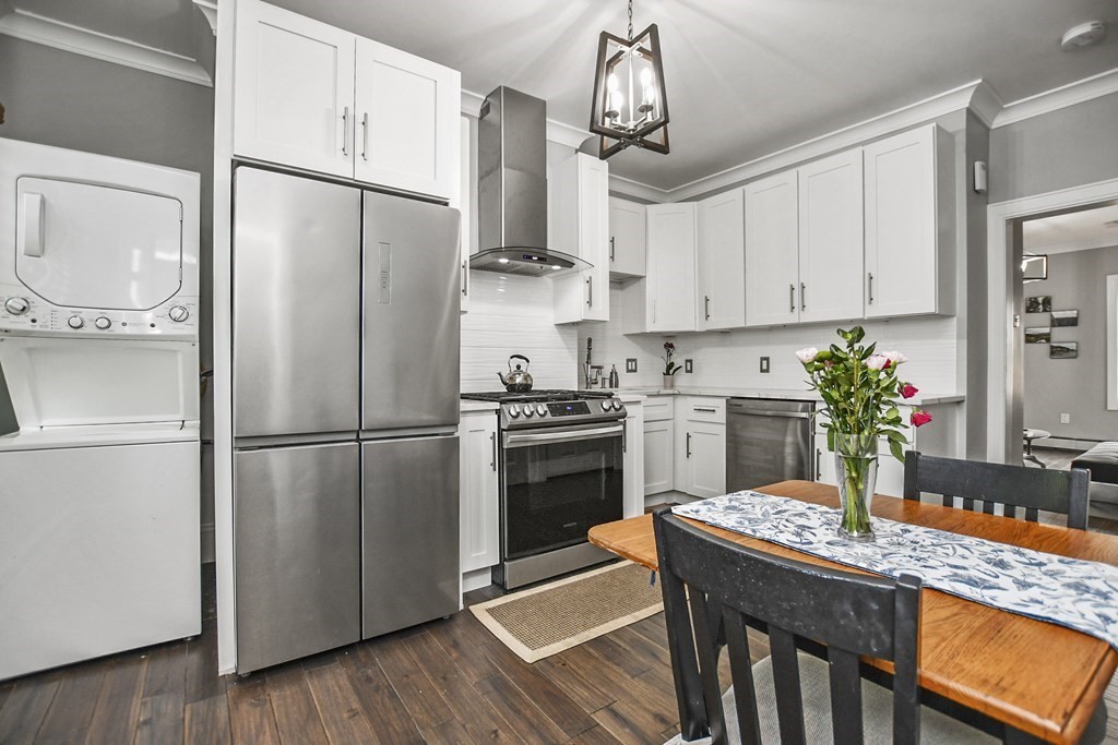 a kitchen with stainless steel appliances granite countertop a refrigerator a sink dishwasher a stove a refrigerator and white cabinets with wooden floor