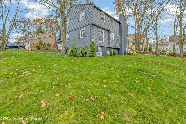 a brick house with a big yard plants and large trees