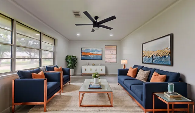 a living room with furniture ceiling fan and a large window