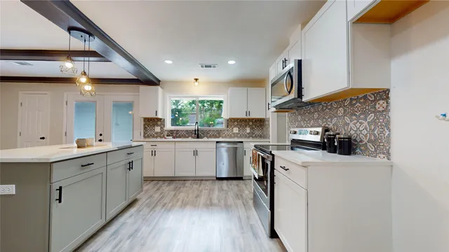 a kitchen with a sink a counter top space stainless steel appliances and cabinets