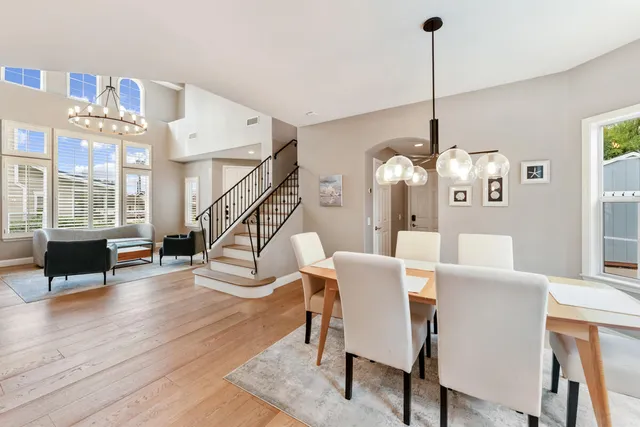 a large open kitchen with a refrigerator a stove a sink a dining table and chairs with wooden floor