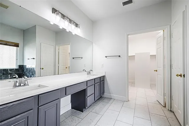 a spacious bathroom with a double vanity sink a mirror and a shower