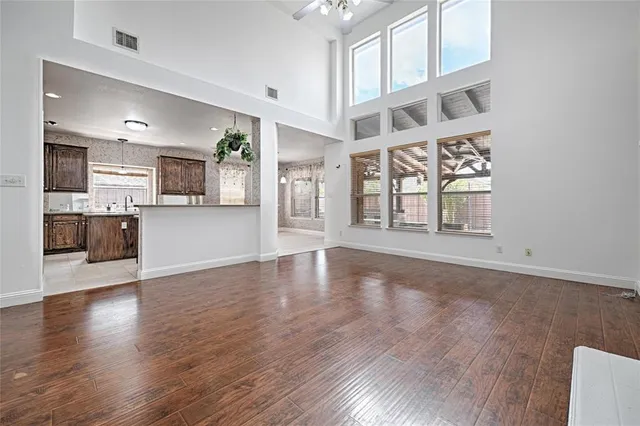 a view of an empty room with kitchen and window