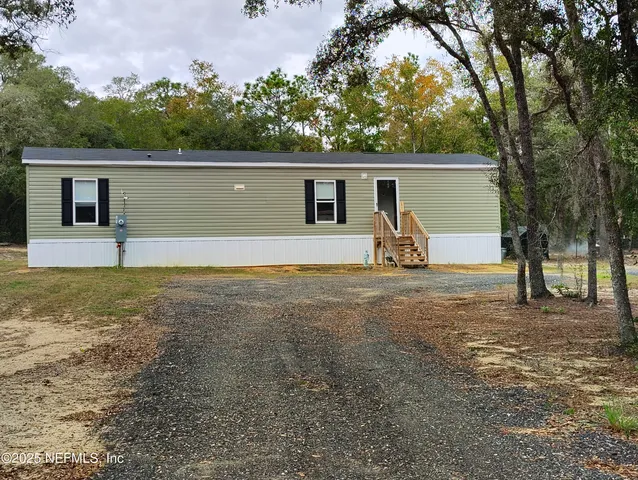 a view of a house with large backyard and a tree