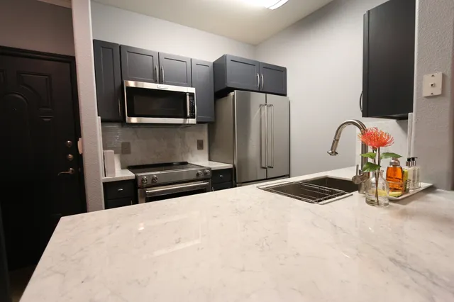 a kitchen with stainless steel appliances a sink a stove a microwave and refrigerator