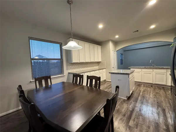 a kitchen with a table chairs a sink dishwasher window and cabinets
