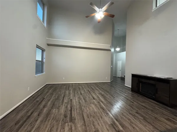 an empty room with wooden floor cabinet and windows