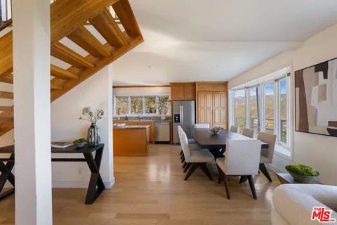 a kitchen with stainless steel appliances granite countertop a stove top oven a sink dishwasher a dining table and chairs with wooden floor