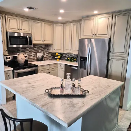 a kitchen with granite countertop a table chairs microwave and refrigerator