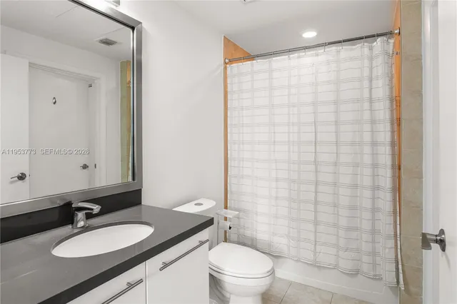 a bathroom with a granite countertop sink toilet a mirror a shower and a mirror