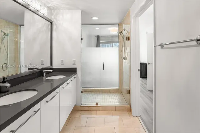 a bathroom with a granite countertop sink mirror and a shower