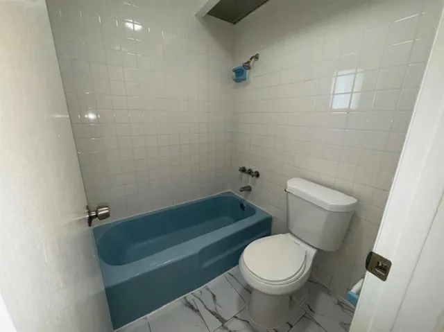 a white toilet sitting next to a bath tub