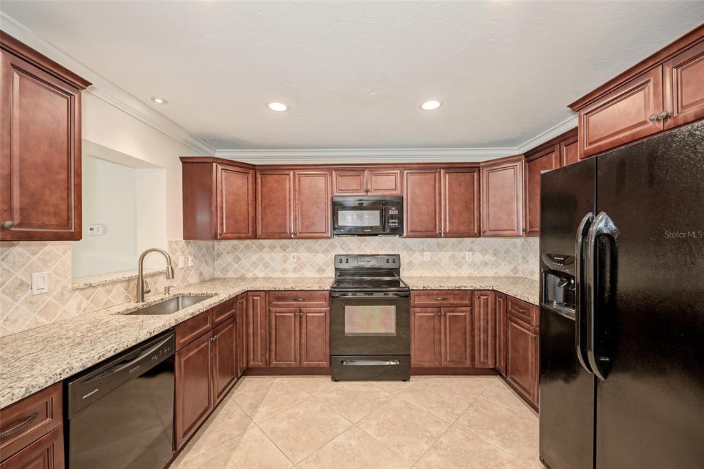 1330 Georgetowne Circle Sarasota, FL 34232 - Photo 13 of 46 a kitchen with stainless steel appliances granite countertop a sink stove refrigerator and cabinets