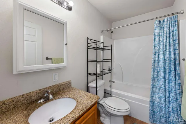 a bathroom with a granite countertop sink toilet a mirror and shower