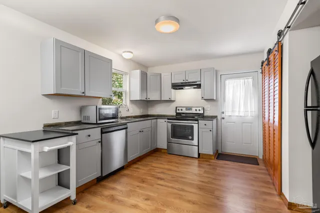 a kitchen with granite countertop a refrigerator stove top oven and sink