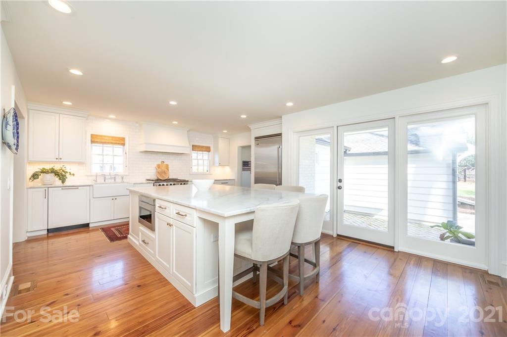 2901 Idlewood Circle Charlotte, NC 28209 - Photo 17 of 48 a kitchen with stainless steel appliances kitchen island wooden floors and white cabinets
