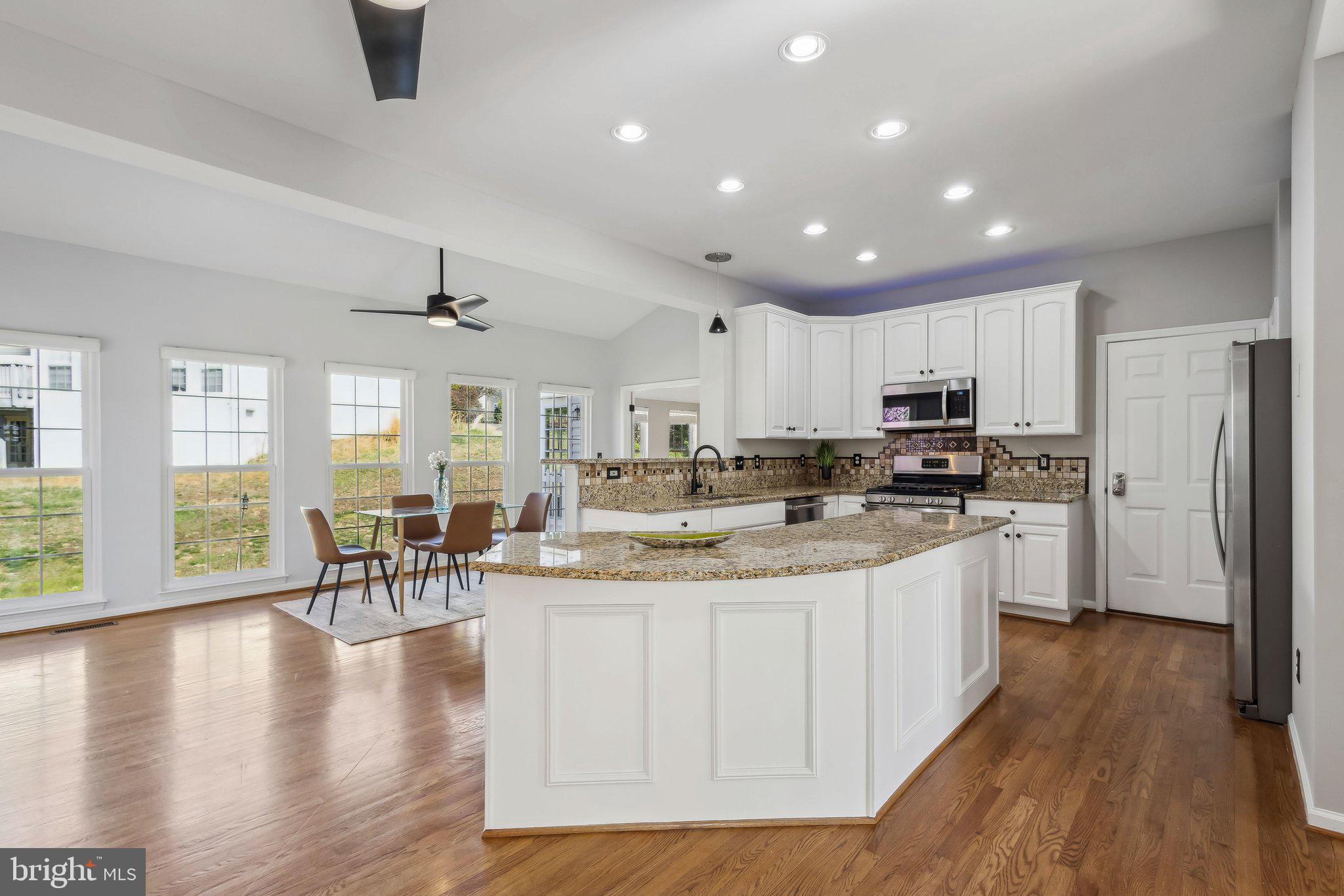 169 Basalt Drive Fredericksburg, VA 22406 - Photo 14 of 56 a kitchen with stainless steel appliances kitchen island granite countertop a stove top oven a sink a dining table and chairs with wooden floor