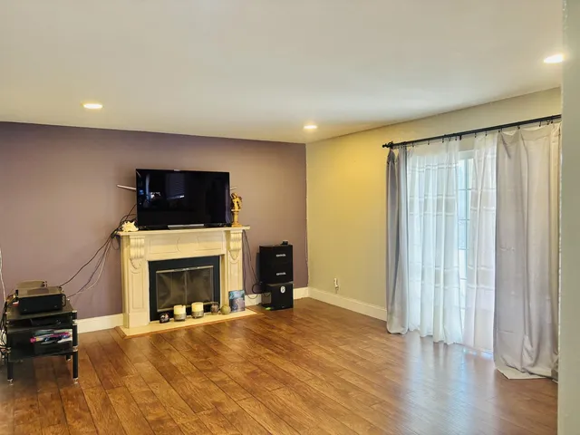 an empty room with wooden floor fireplace and windows