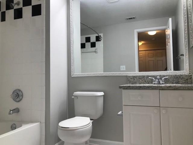 599 Campus Street, Unit 599 Celebration, FL 34747 - Photo 11 of 24 a bathroom with a granite countertop sink a mirror and a toilet