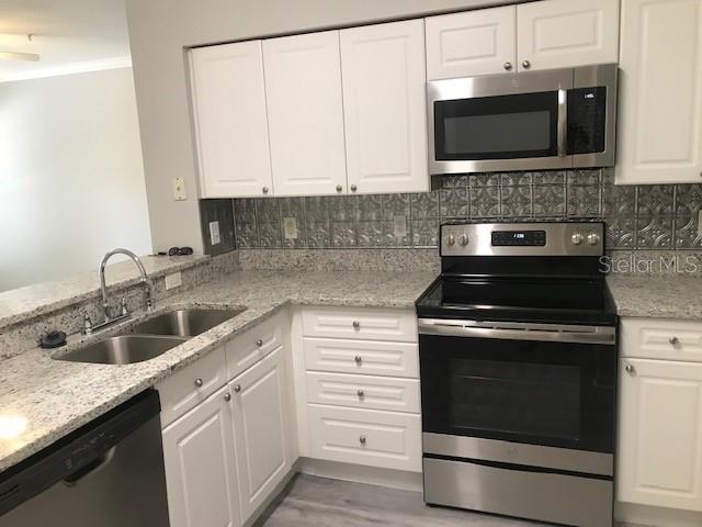 599 Campus Street, Unit 599 Celebration, FL 34747 - Photo 4 of 24 a kitchen with granite countertop white cabinets sink and stainless steel appliances