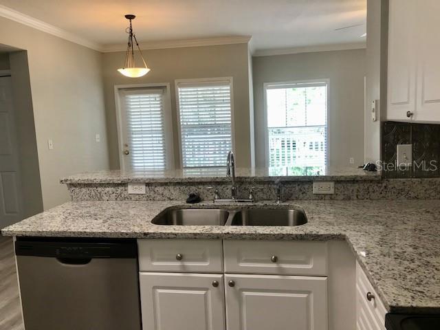 599 Campus Street, Unit 599 Celebration, FL 34747 - Photo 5 of 24 a kitchen with granite countertop a sink and a white wooden cabinets