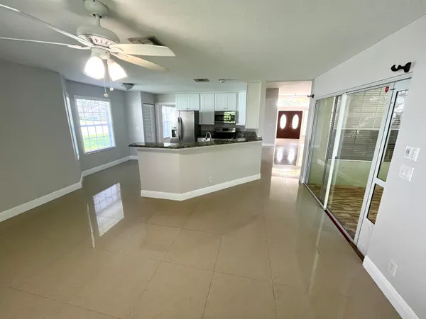 a view of an empty room with window and chandelier fan