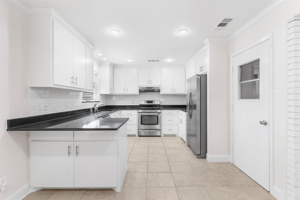 831 Warren Way Richardson, TX 75080 - Photo 5 of 18 a kitchen with white cabinets and stainless steel appliances