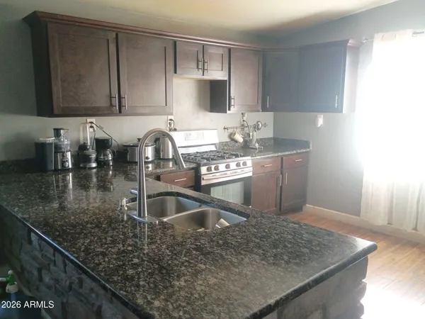 a kitchen with a sink and a stove top oven with wooden floor