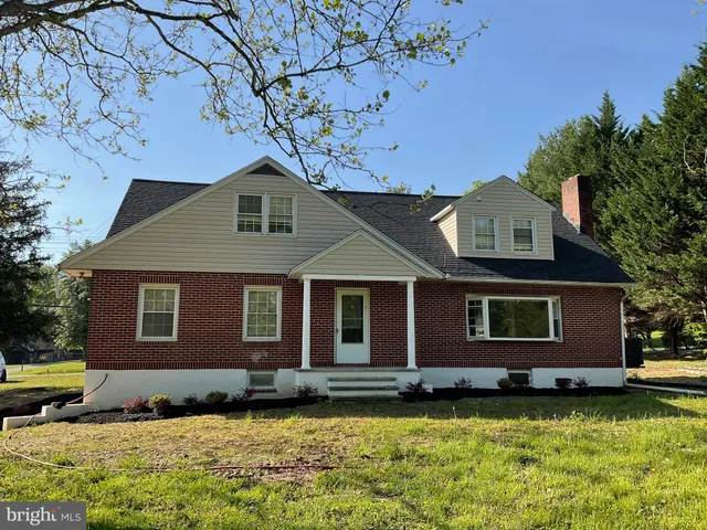 a view of a white house next to a yard with big trees