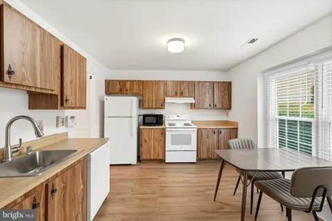 a kitchen with a table chairs a sink dishwasher refrigerator and cabinets