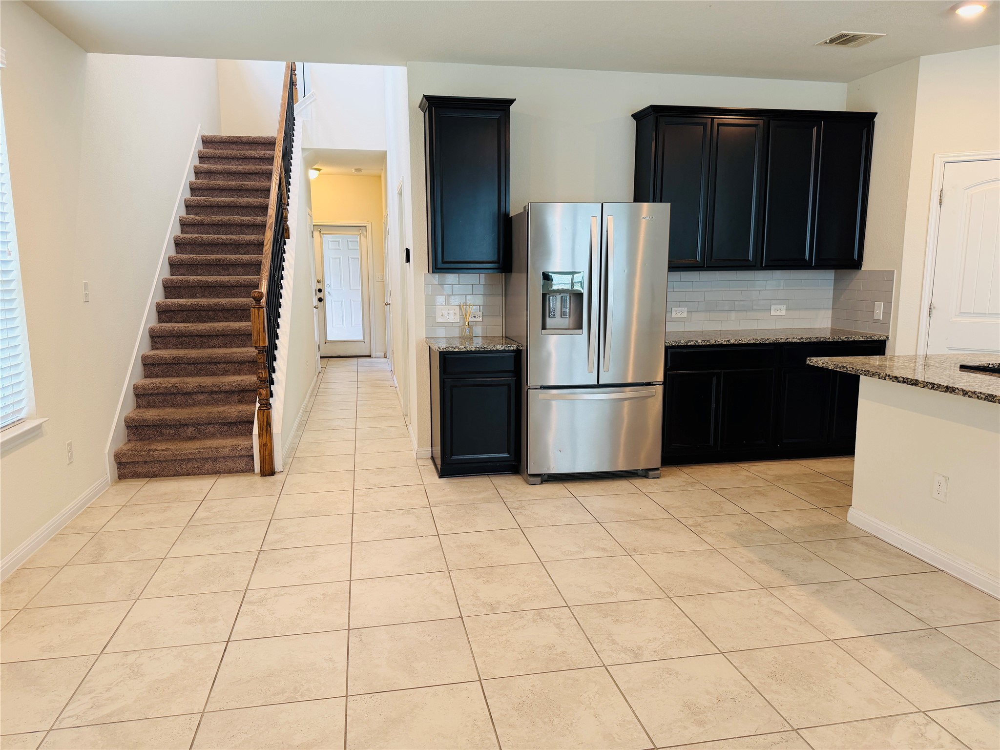 2013 Hat Bender Loop Round Rock, TX 78664 - Photo 3 of 16 Kitchen with light stone countertops, dark cabinetry, stainless steel fridge with ice dispenser, light tile patterned floors, and backsplash