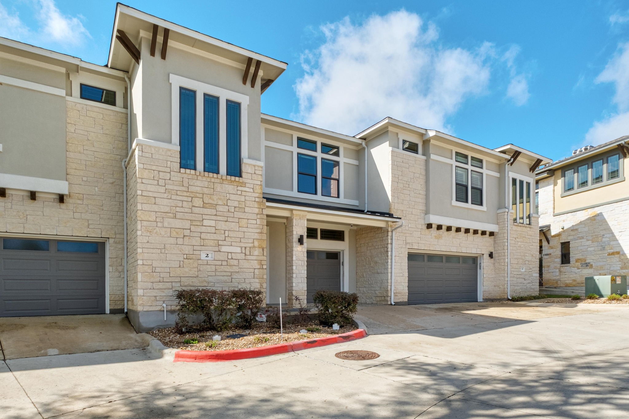 4323 Spicewood Springs Road, Unit 2 Austin, TX 78759 - Photo 30 of 30 View of front of house featuring a garage, driveway, stucco siding, and stone siding
