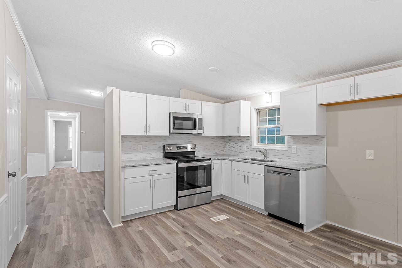 1002 Autry Road Lillington, NC 27546 - Photo 11 of 38 a kitchen with stainless steel appliances granite countertop a stove top oven a sink dishwasher and a refrigerator with wooden floor