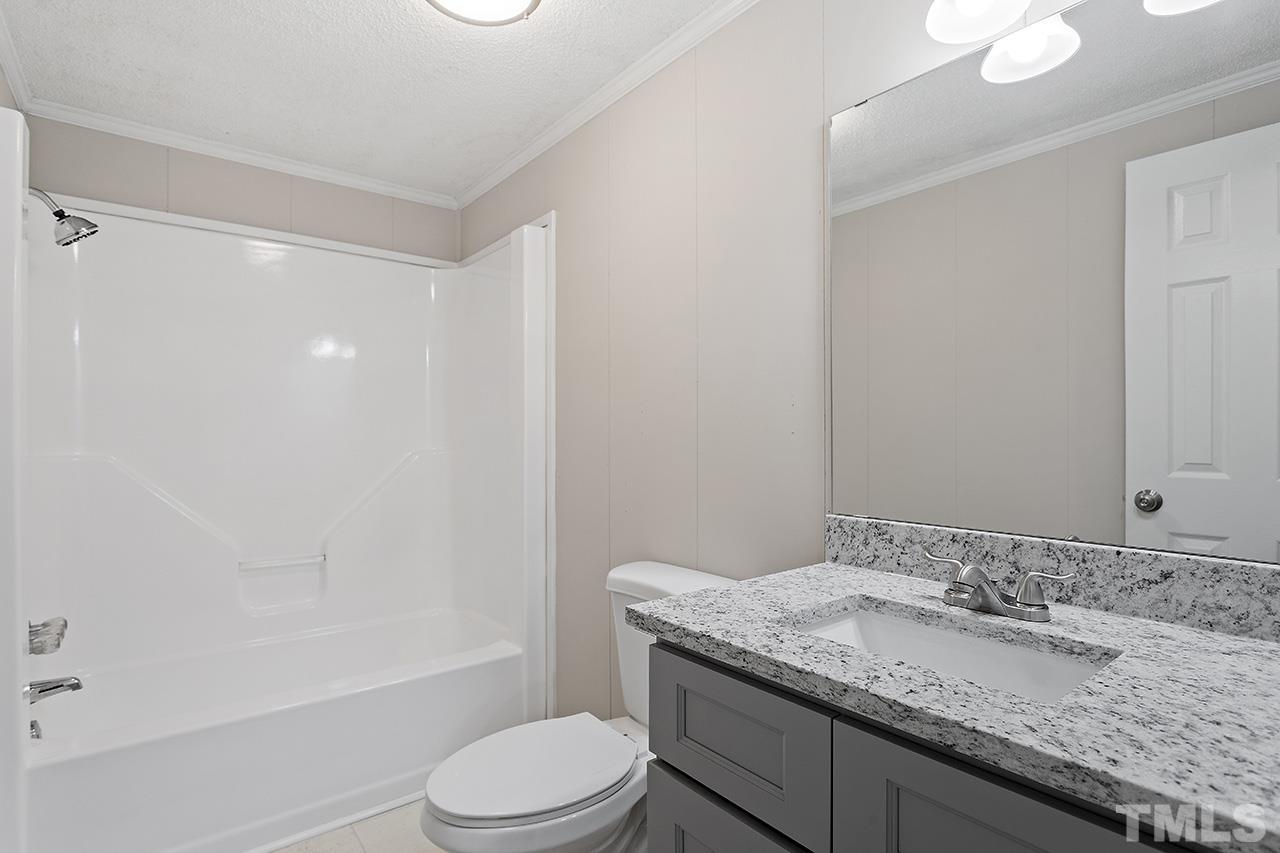 1002 Autry Road Lillington, NC 27546 - Photo 22 of 38 a bathroom with a granite countertop sink a toilet and shower