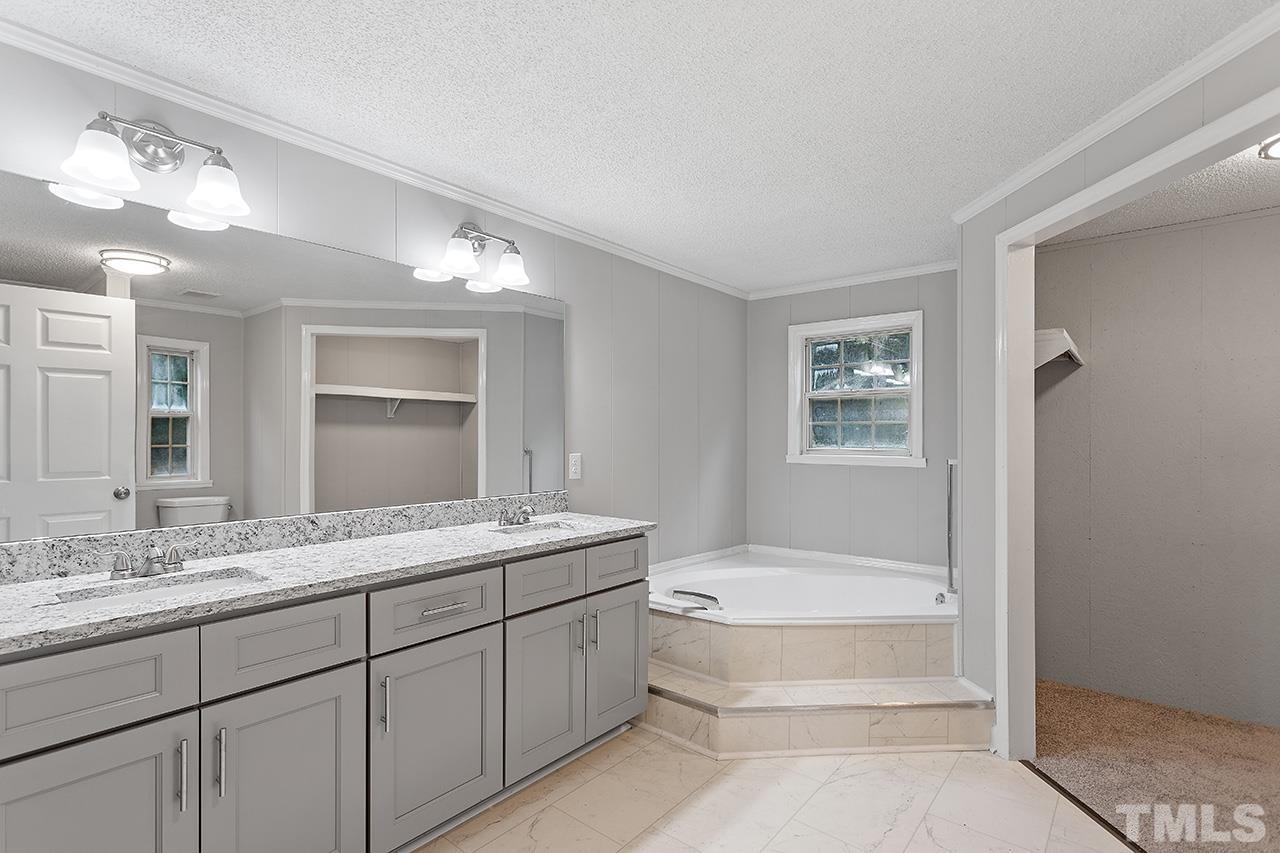 1002 Autry Road Lillington, NC 27546 - Photo 8 of 38 a bathroom with a tub a sink and mirror