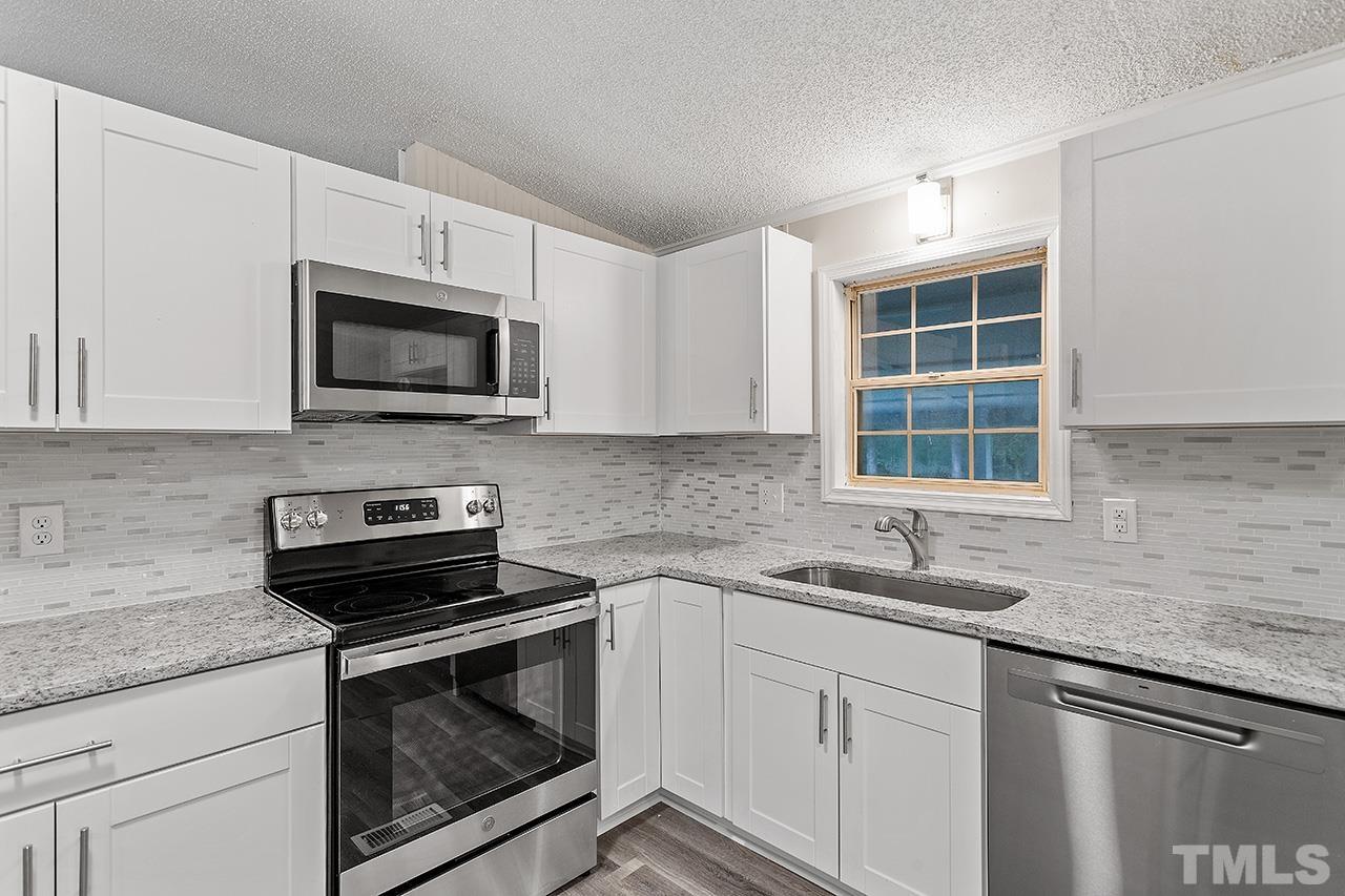1002 Autry Road Lillington, NC 27546 - Photo 9 of 38 a kitchen with granite countertop a sink stove top oven and microwave