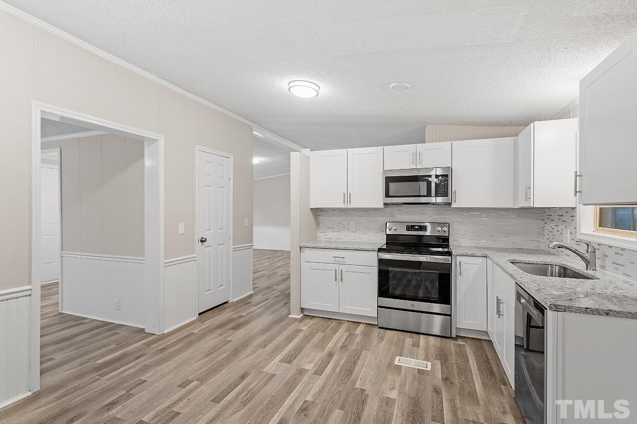 1002 Autry Road Lillington, NC 27546 - Photo 10 of 38 a kitchen with cabinets appliances and a wooden floor