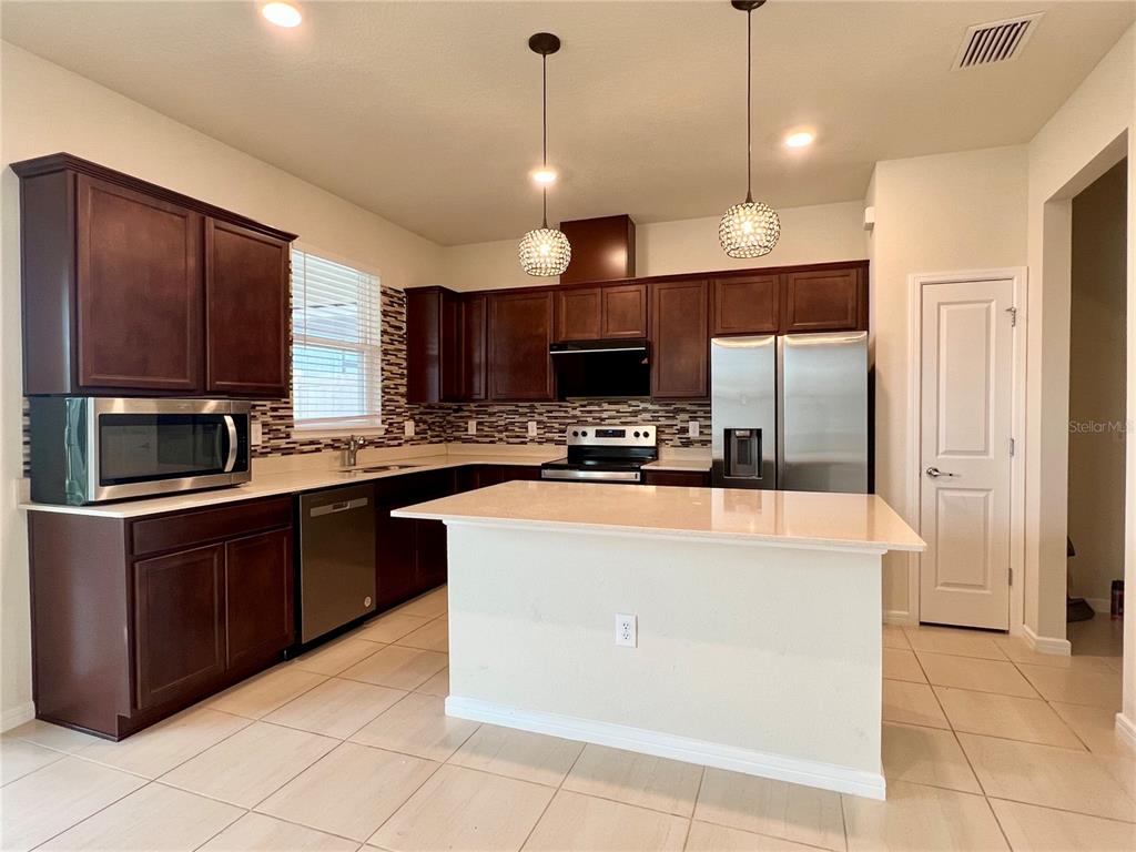 7488 Catania Loop Clermont, FL 34714 - Photo 5 of 22 a kitchen with stainless steel appliances granite countertop a refrigerator a stove a sink and a microwave