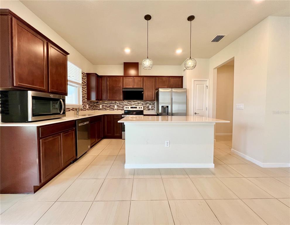 7488 Catania Loop Clermont, FL 34714 - Photo 5 of 31 a large kitchen with stainless steel appliances granite countertop a stove a sink a microwave and a refrigerator