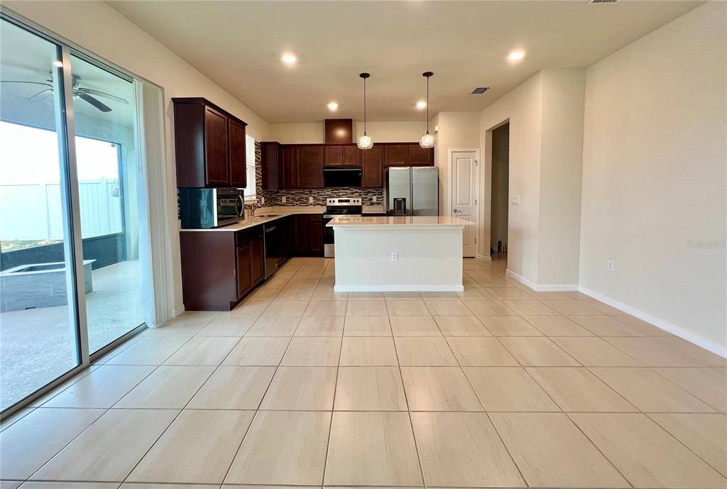 7488 Catania Loop Clermont, FL 34714 - Photo 6 of 22 a large kitchen with stainless steel appliances kitchen island granite countertop a refrigerator and a stove top oven