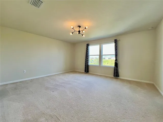 an empty room with windows and chandelier fan