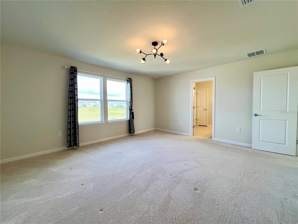 7488 Catania Loop Clermont, FL 34714 - Photo 9 of 31 an empty room with windows and chandelier fan