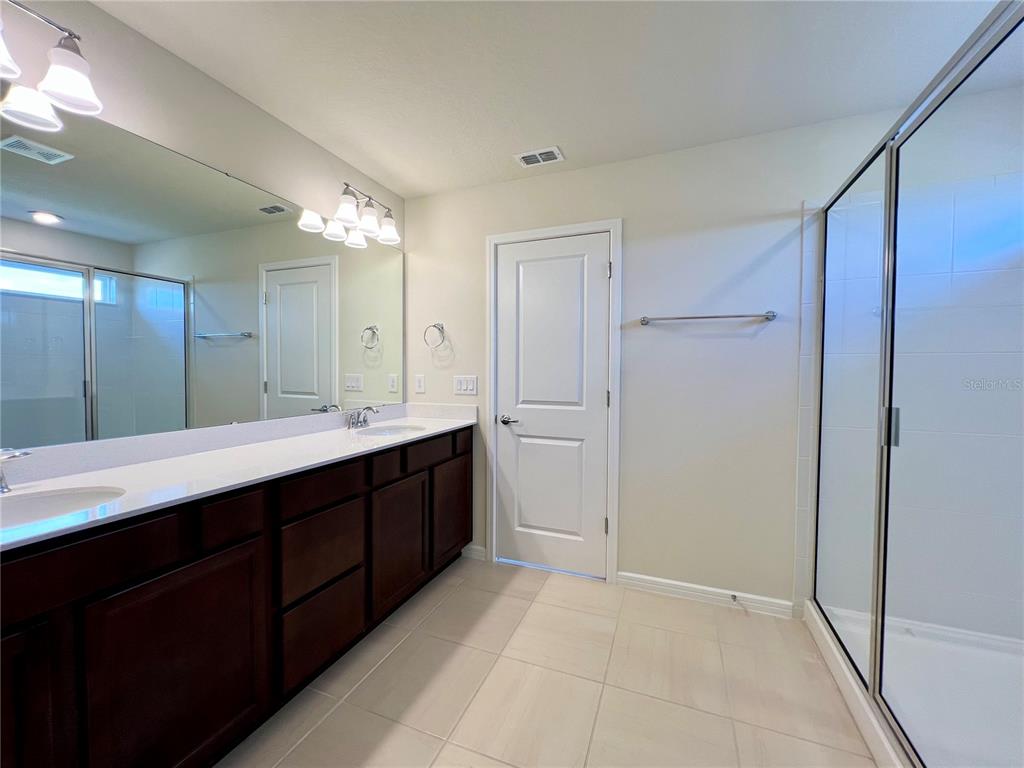 7488 Catania Loop Clermont, FL 34714 - Photo 10 of 31 a bathroom with a double vanity sink a mirror and a shower